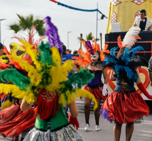 T&auml;nzerinnen in bunten Federkost&uuml;men und Masken feiern ausgelassen auf einer Stra&szlig;e beim Karnevalsumzug auf Grenada.