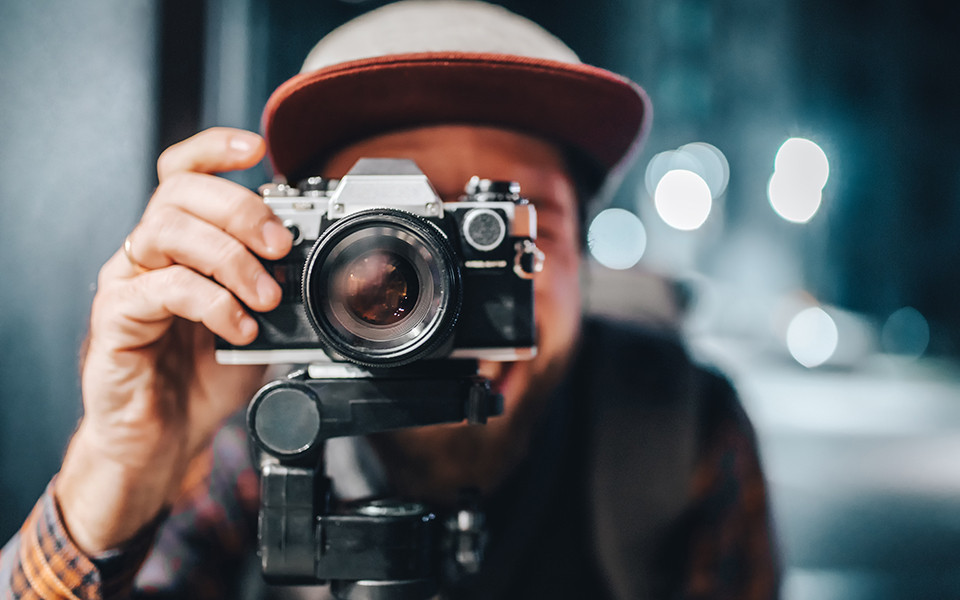 Mann mit Kamera auf Stativ