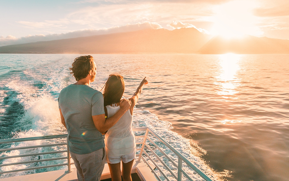 Paar an Deck eines Kreuzfahrtschiffes genie&szlig;t den Sonnenuntergang 