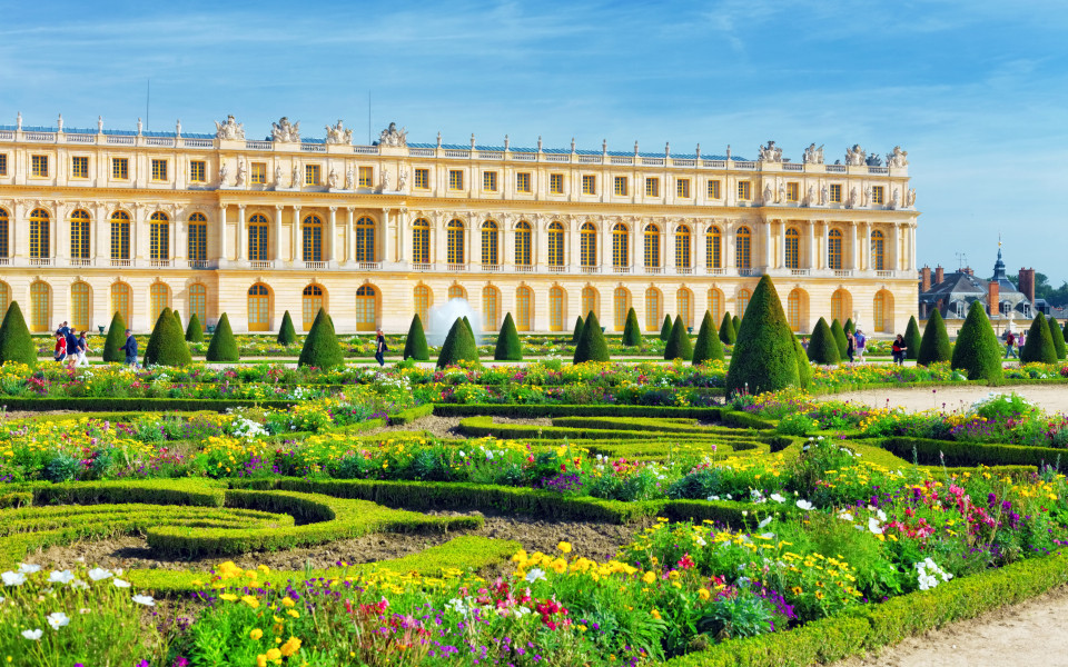 Prunkvolles Schloss Versailles bei Paris mit barockem Garten und farbenpr&auml;chtigen Blumenbeeten.